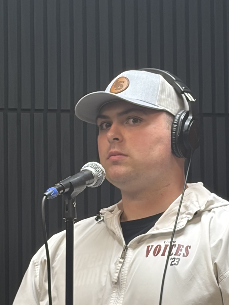 Caleb at a studio microphone wearing headphones